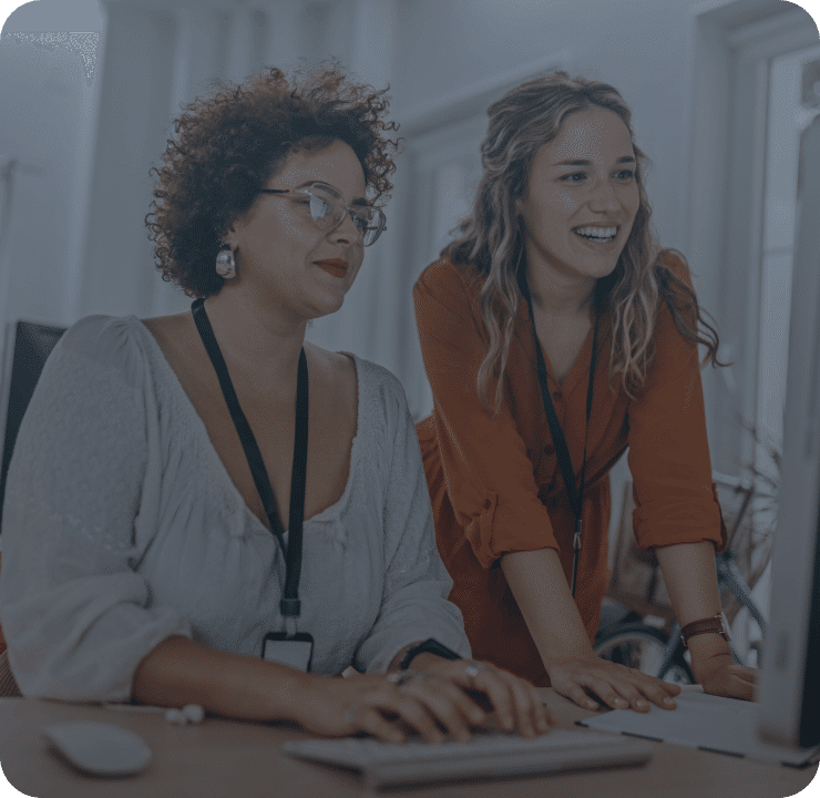 Two women smiling and working on a computer together