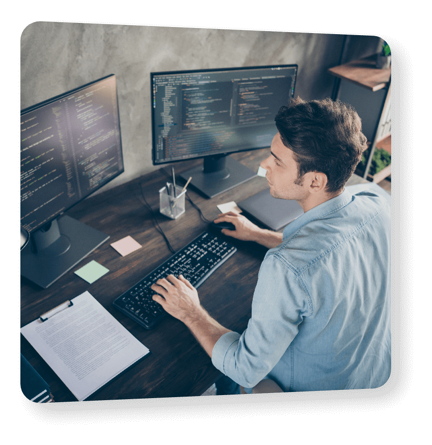Man coding on dual monitors at a desk