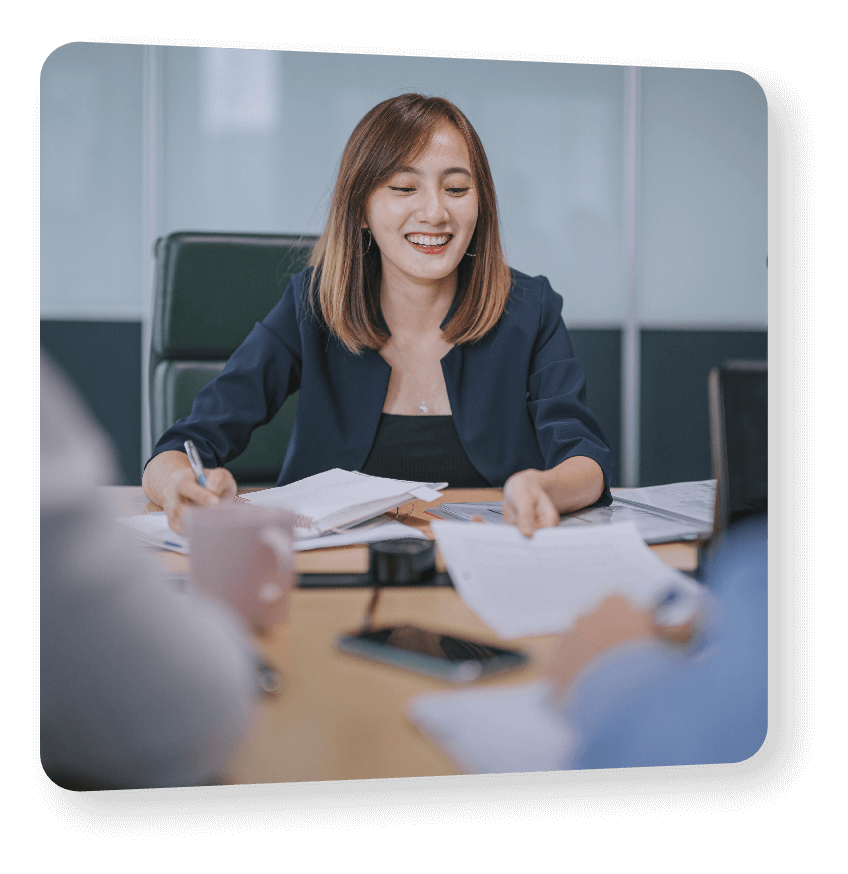 Businesswoman smiling sitting at a boardroom table with documents